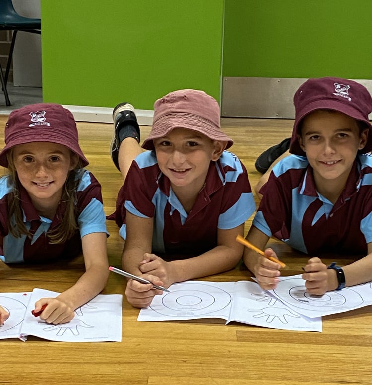 3 students laying on floor completing work