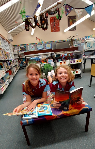 2 students enjoying reading in the library