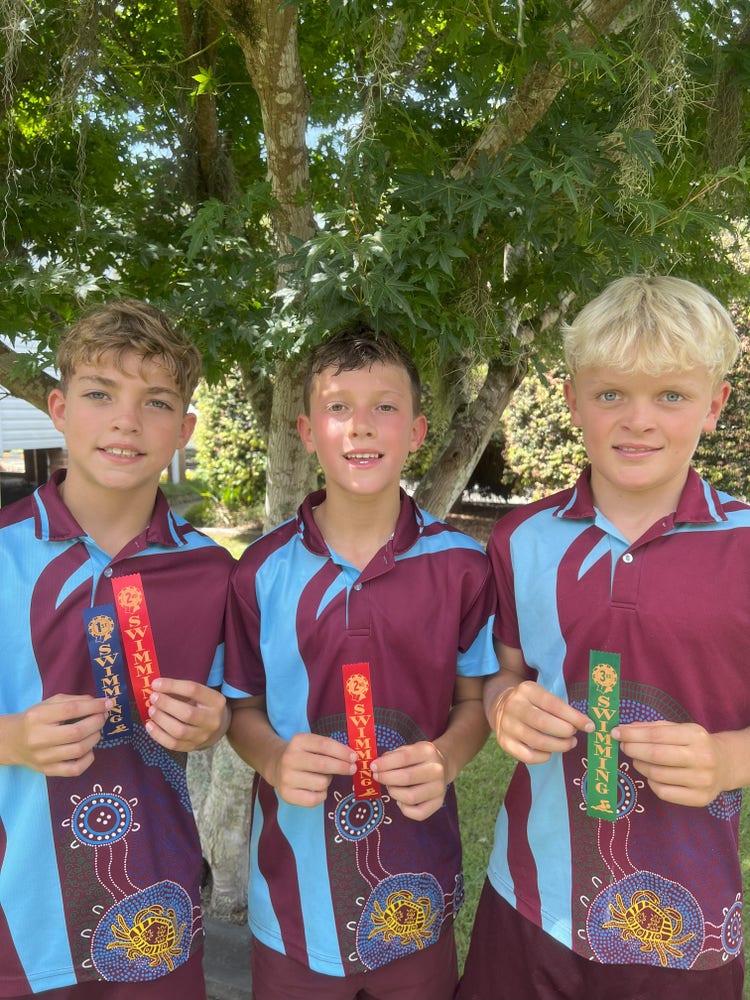 3 students proudly showing their athletics ribbons